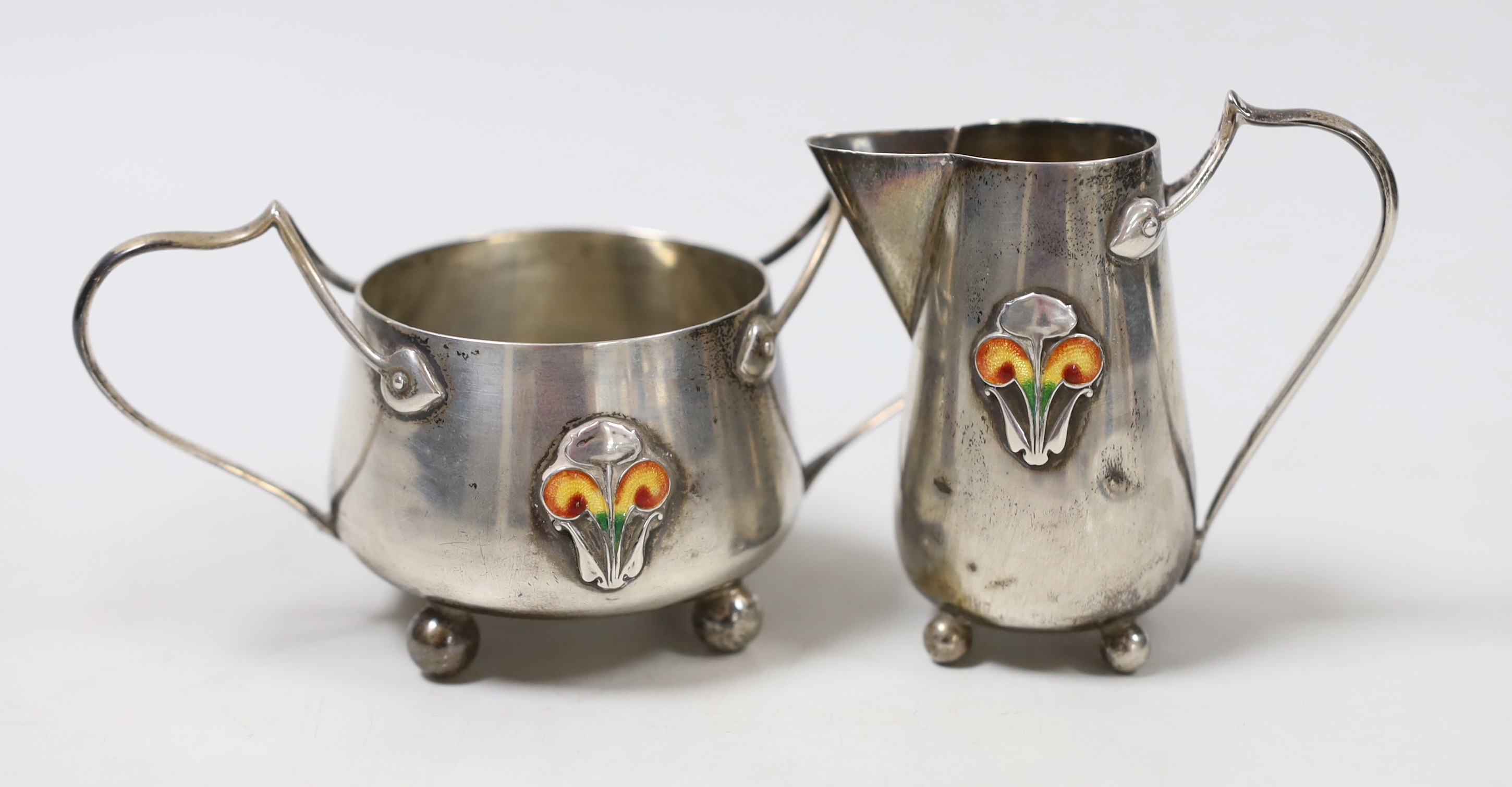 An Edwardian Art Nouveau silver and enamelled cream jug and sugar bowl, C & Co, Birmingham, 1905, jug height 76mm, gross weight 123 grams.